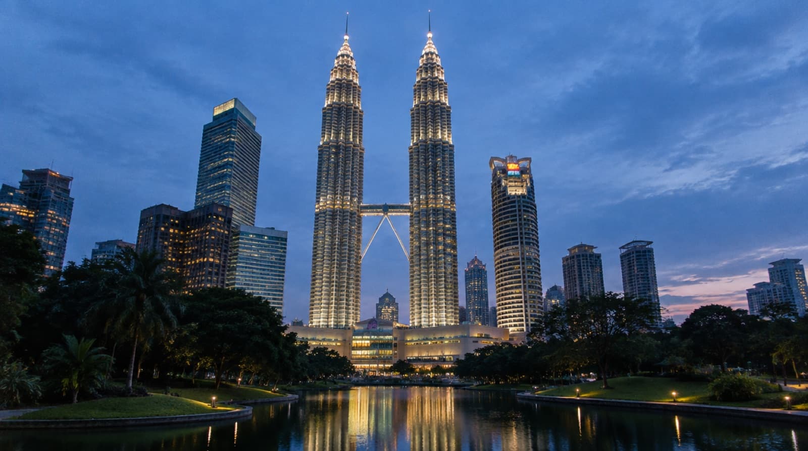 The Petronas Twin Towers lit at dusk above the KLCC park in Kuala Lumpur