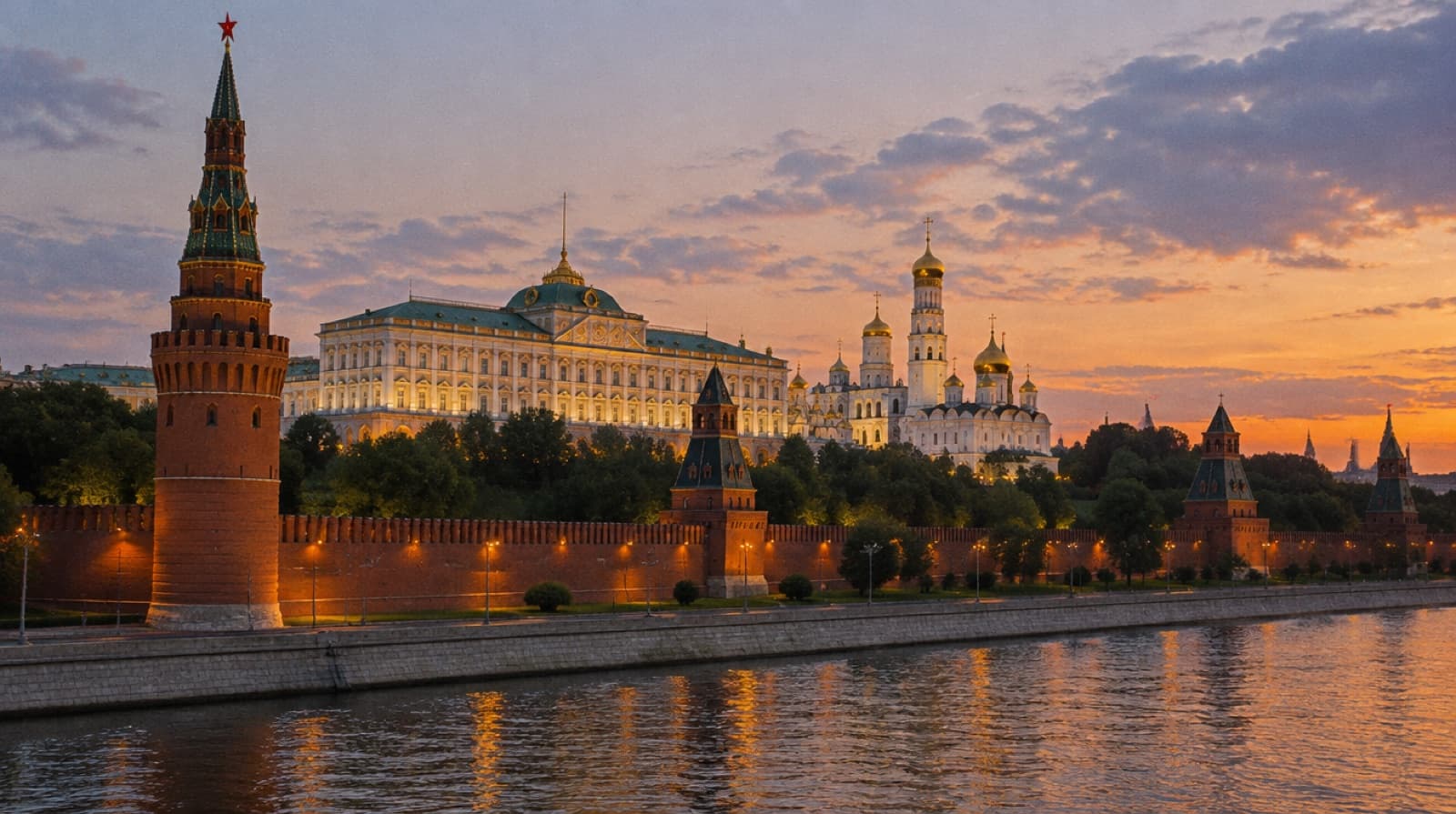 The Moscow Kremlin walls and cathedral domes along the river at sunset